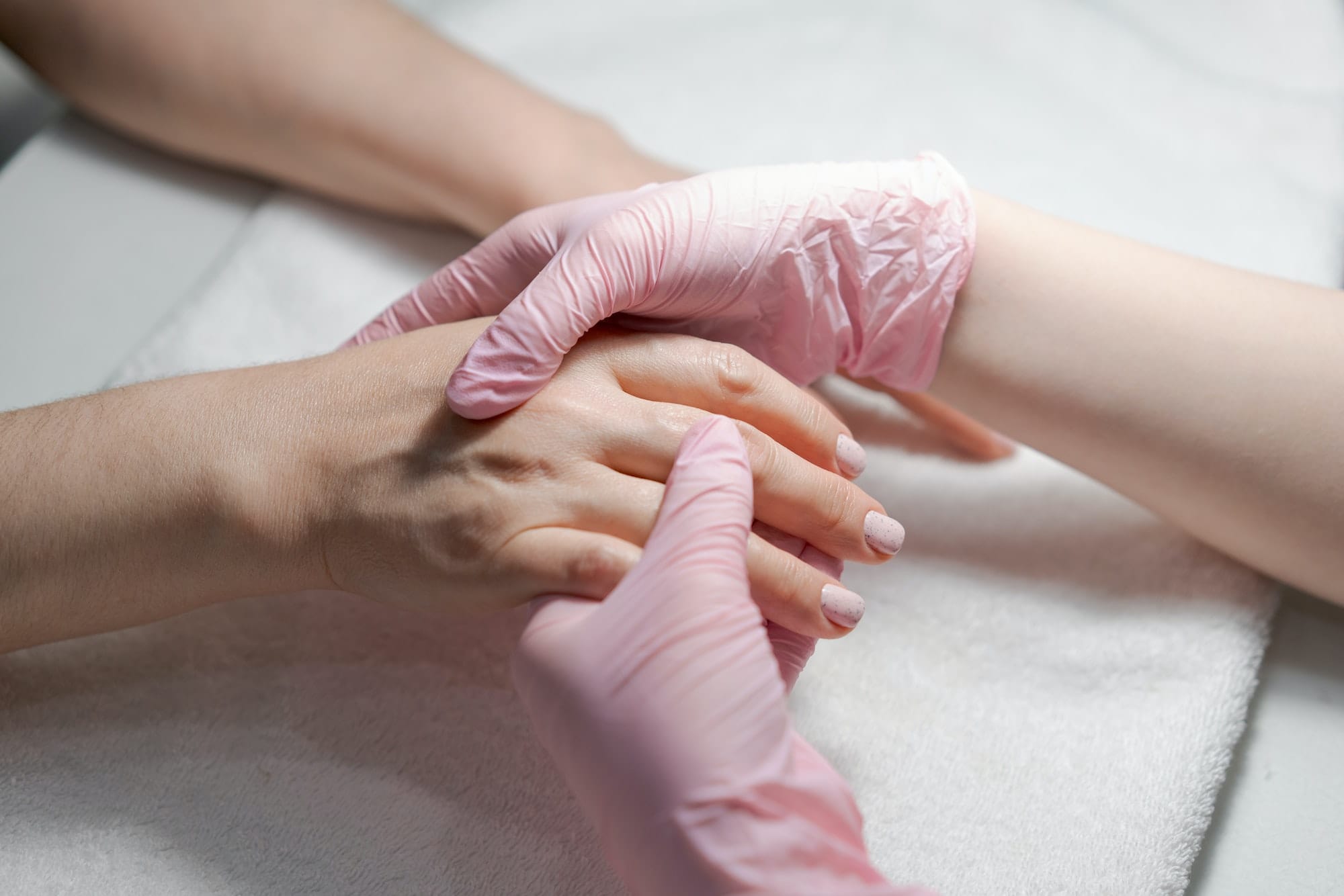 Close-up hands beautician, woman's hands receive manicure treatment, master